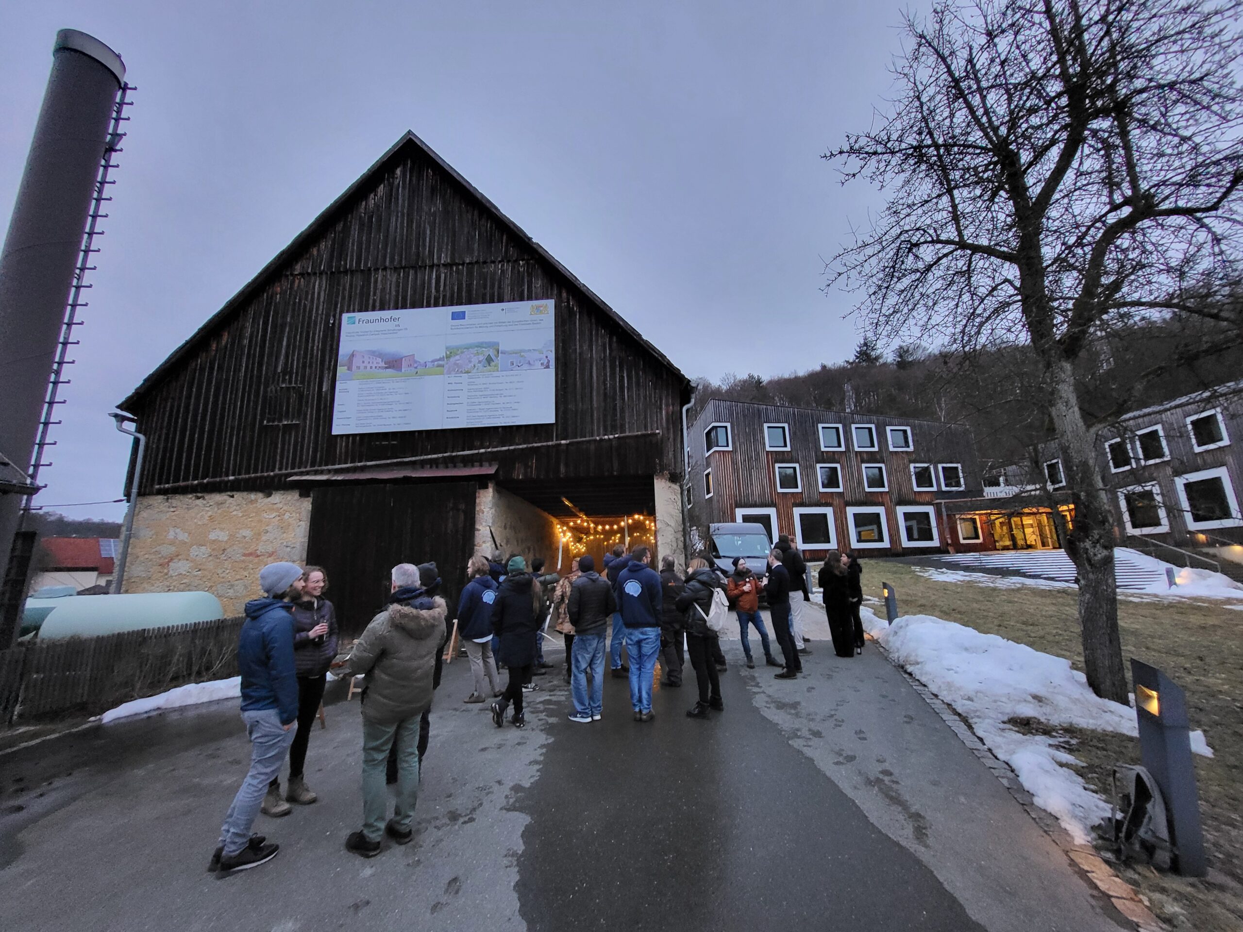 Evening gathering at the Fraunhofer campus, with colleagues chatting and archery under the roof. (Image: A. Dakkouri-Baldauf)